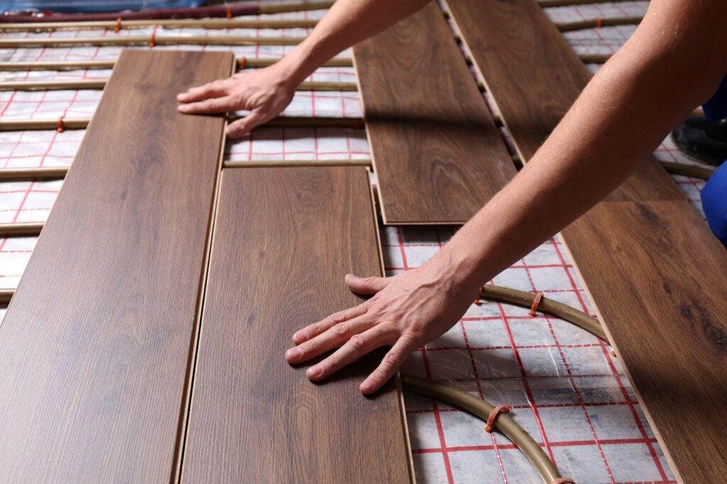 A worker applying wood flooring to a floor demonstrating skill in the placement of each plank
