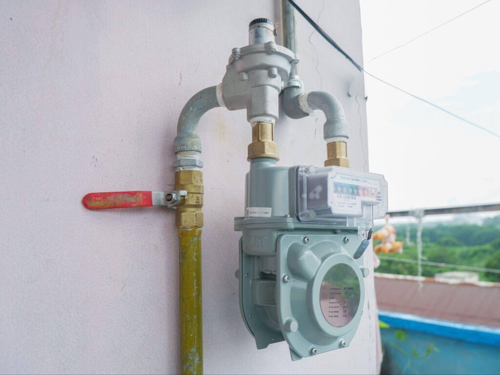 A meter affixed to a wall featuring a hose attached for monitoring fluid flow or pressure