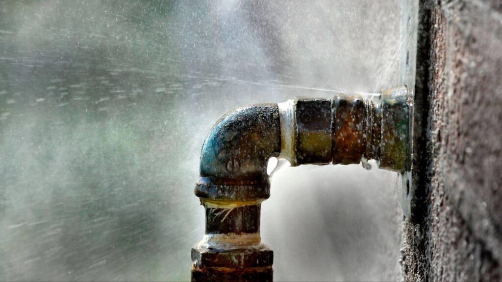 A close up of a leaking water pipe on a weathered brick wall highlighting material interaction