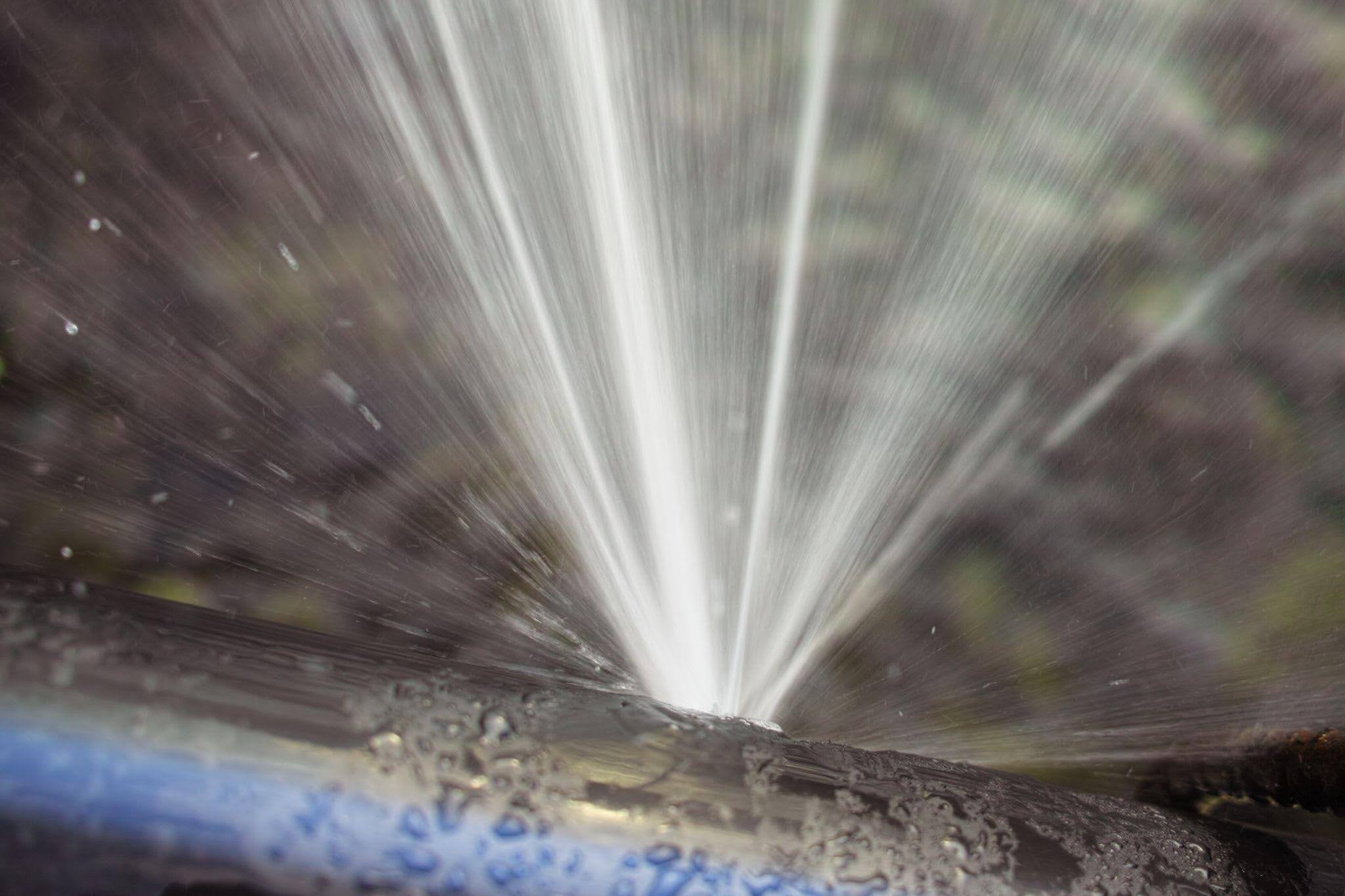 Close up of a water hose spraying a fine mist of water against a blurred background