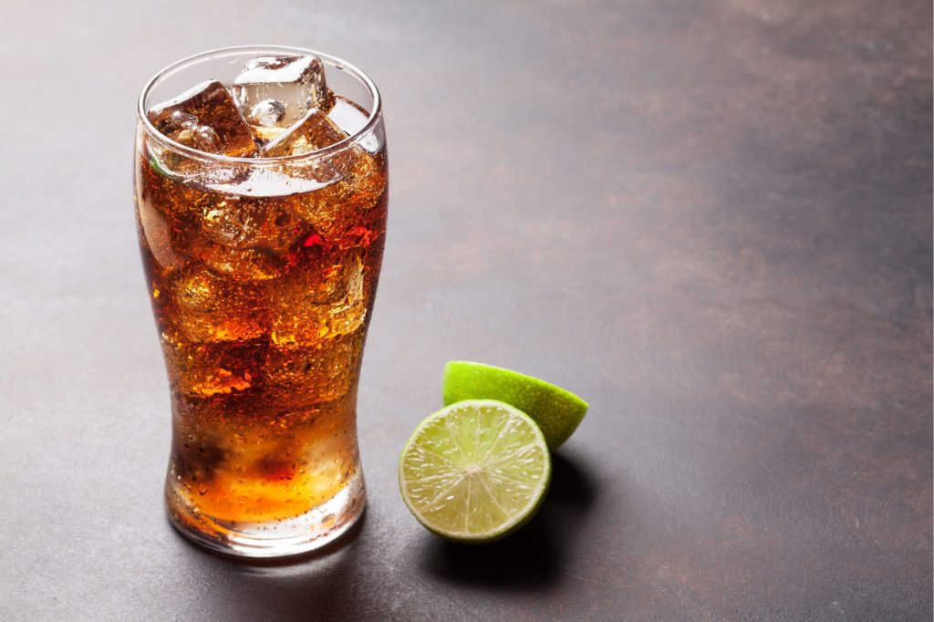 A clear glass filled with cola and ice cubes.