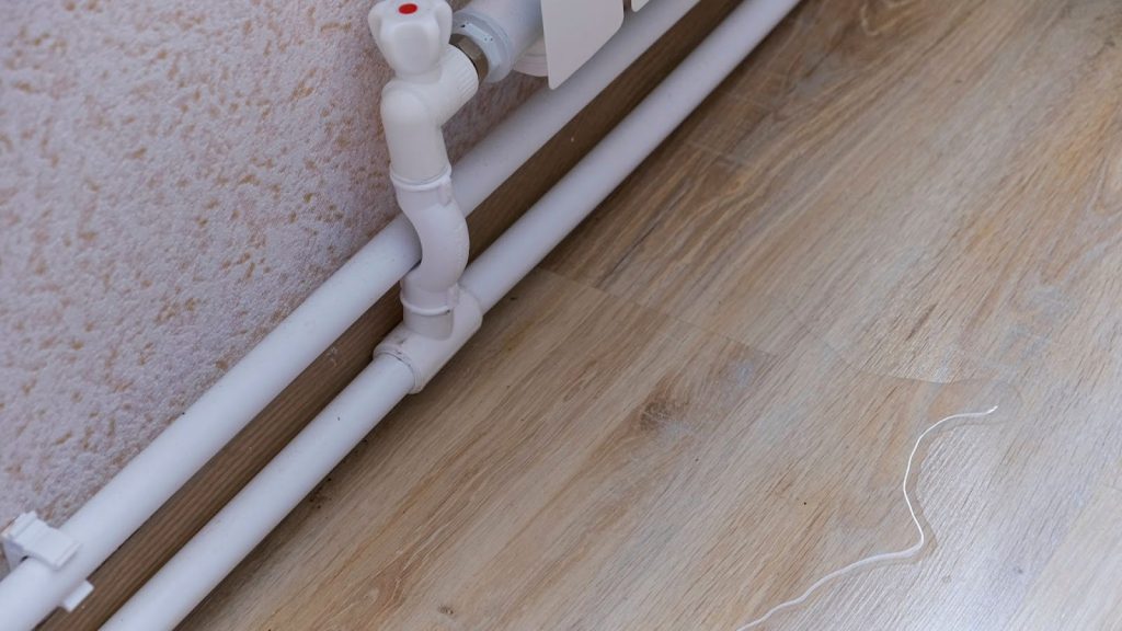 White pipe with plug on floor, part of plumbing system