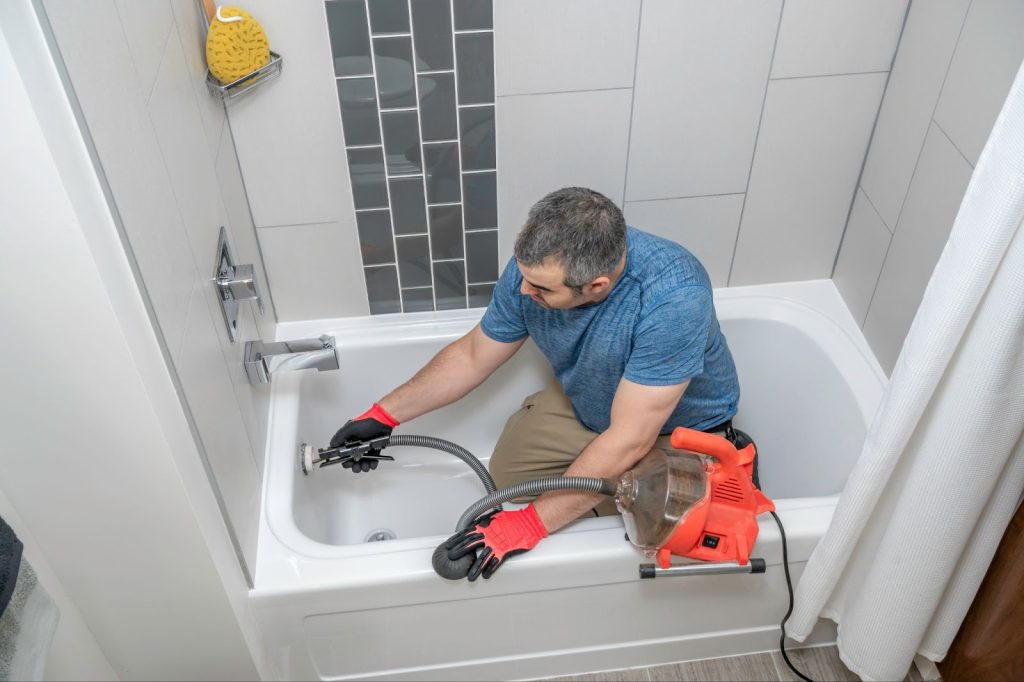 A bathtub with plumbing issues, showing water leaking from the faucet and drain