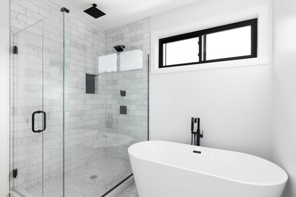 Bathroom with white tub and glass shower door.