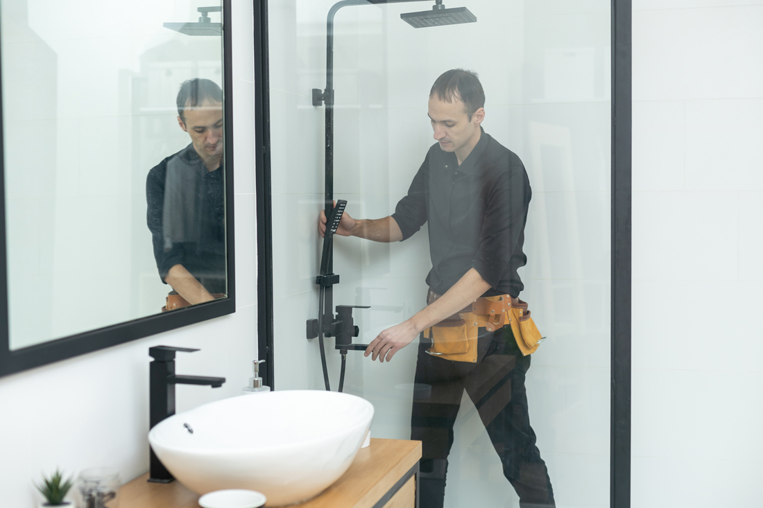 Close-up of a plumber repairing a leaking shower.