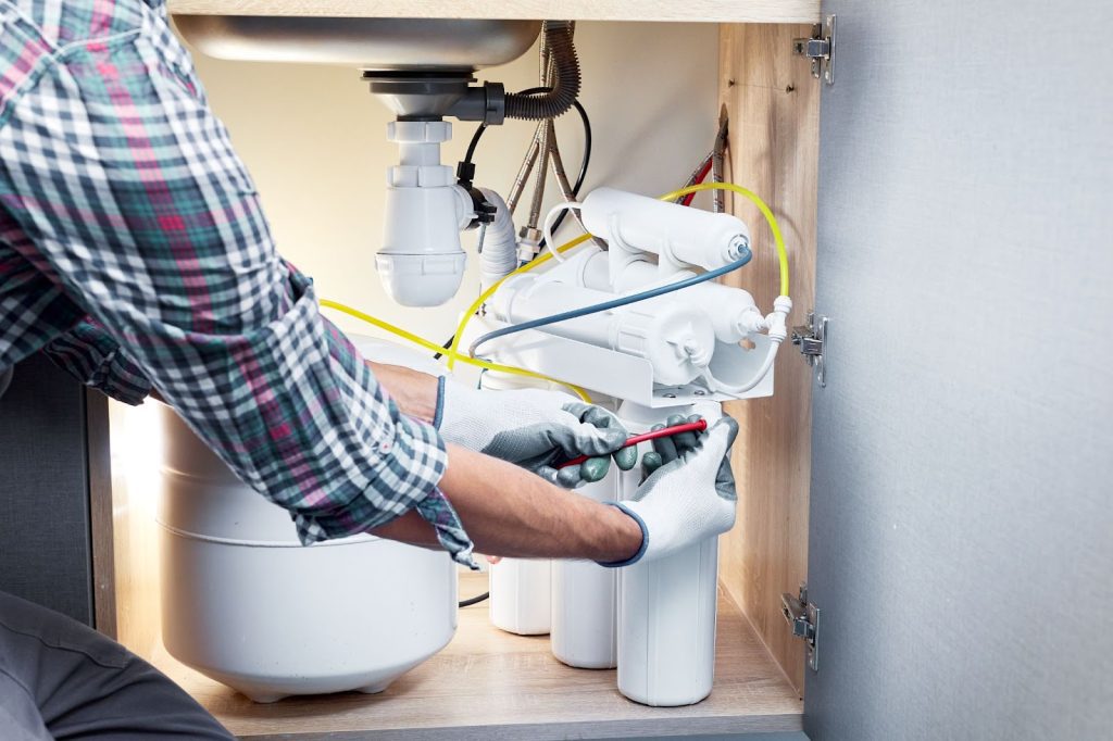 A man installing a water filter in a kitchen, ensuring improved water quality for residential use