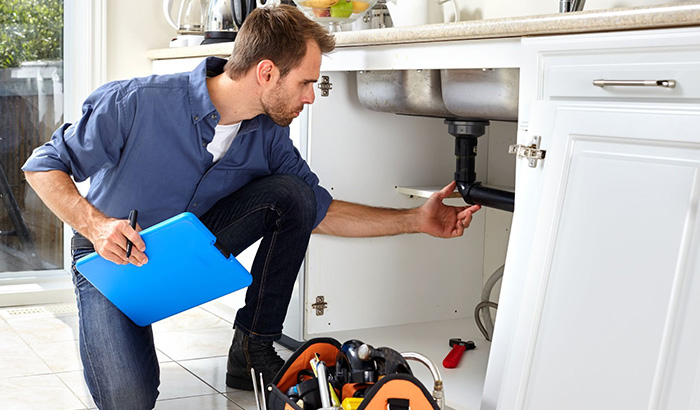 Professional plumber checking a sink in a residential building
