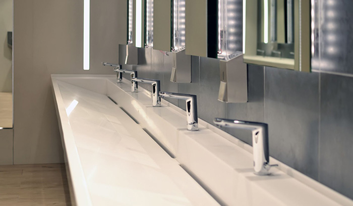 White bathroom counter in commercial setting with plumbing services and systems by professional plumber
