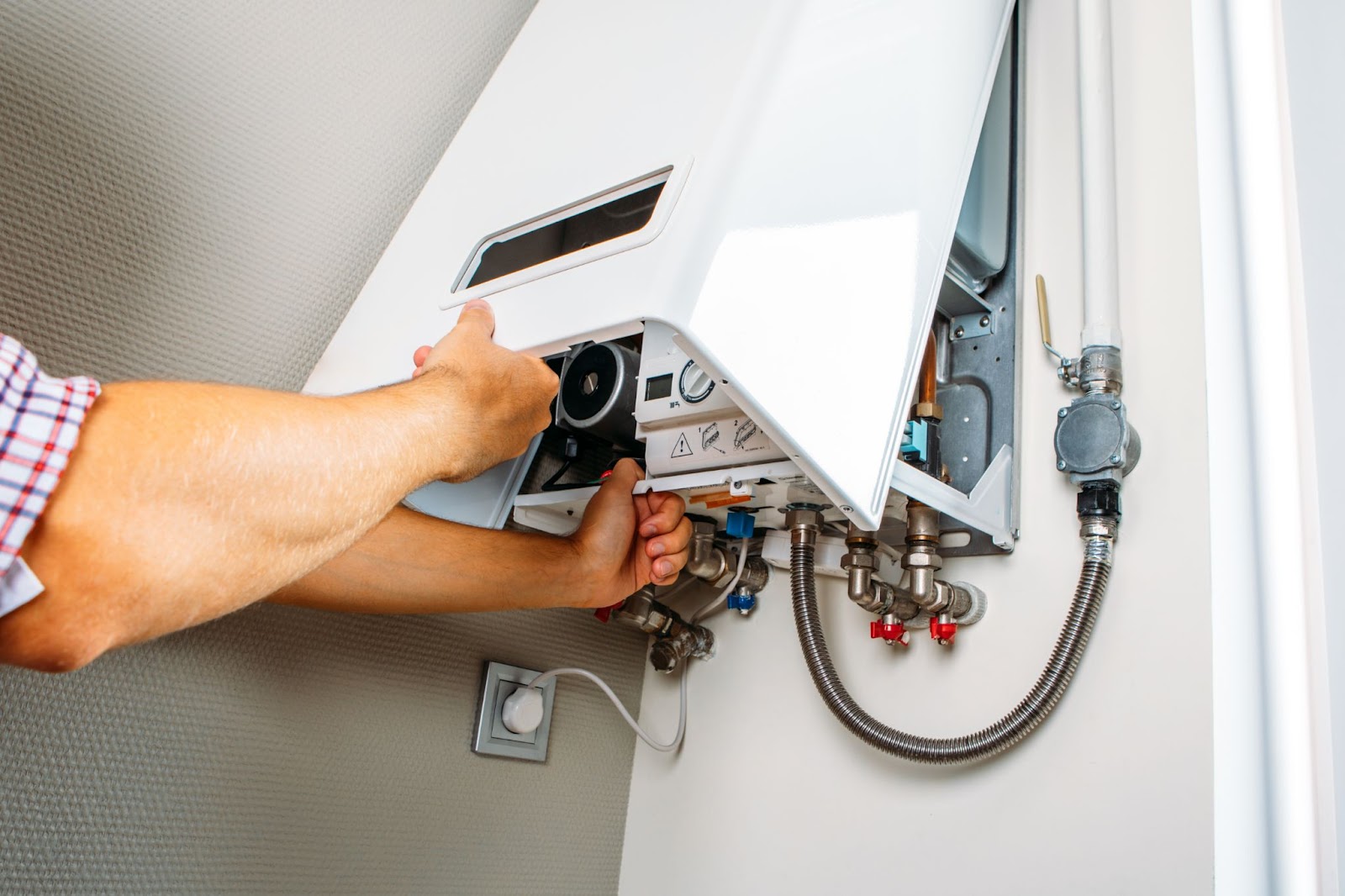 A person repairing an open boiler with visible pipes and components.