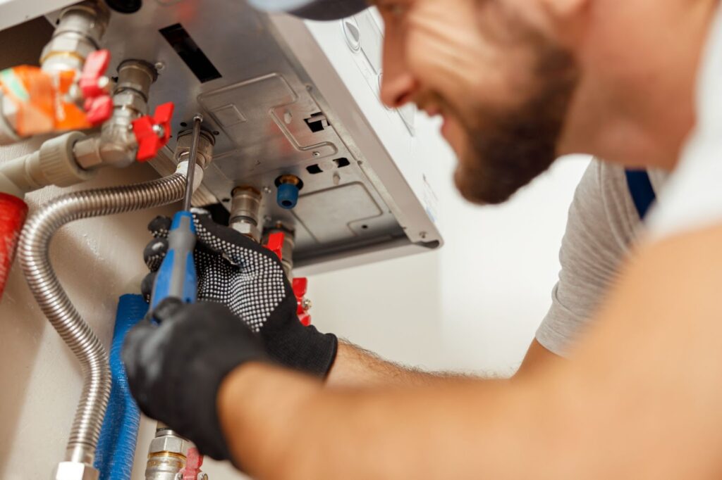 A plumber working on a water heater with tools and pipes.