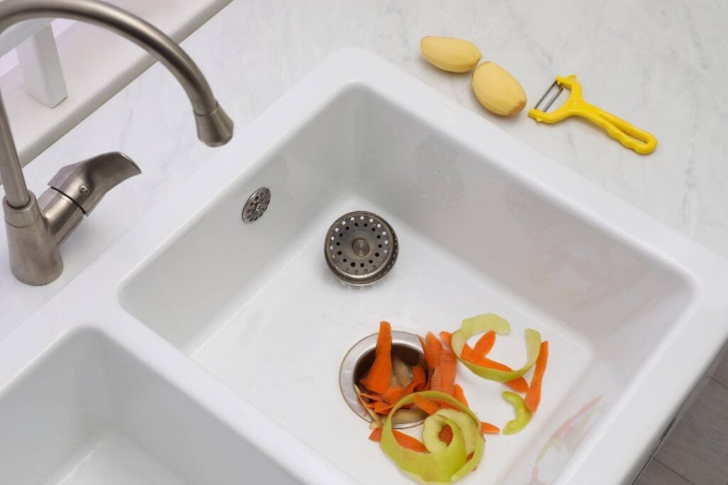 A kitchen sink filled with fresh vegetables and a modern faucet above