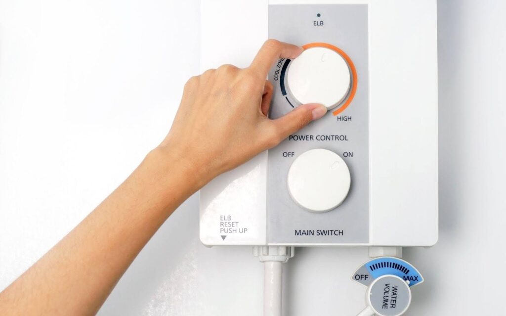 A person pressing the button on a water heater adjusting the temperature settings for hot water