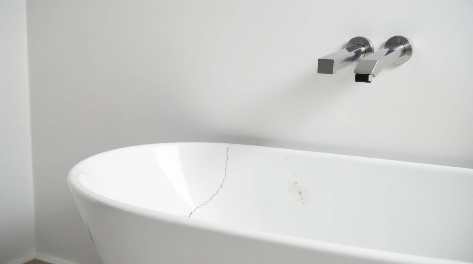 A sleek white bathtub located in a stylish bathroom surrounded by light-colored walls and elegant fixtures