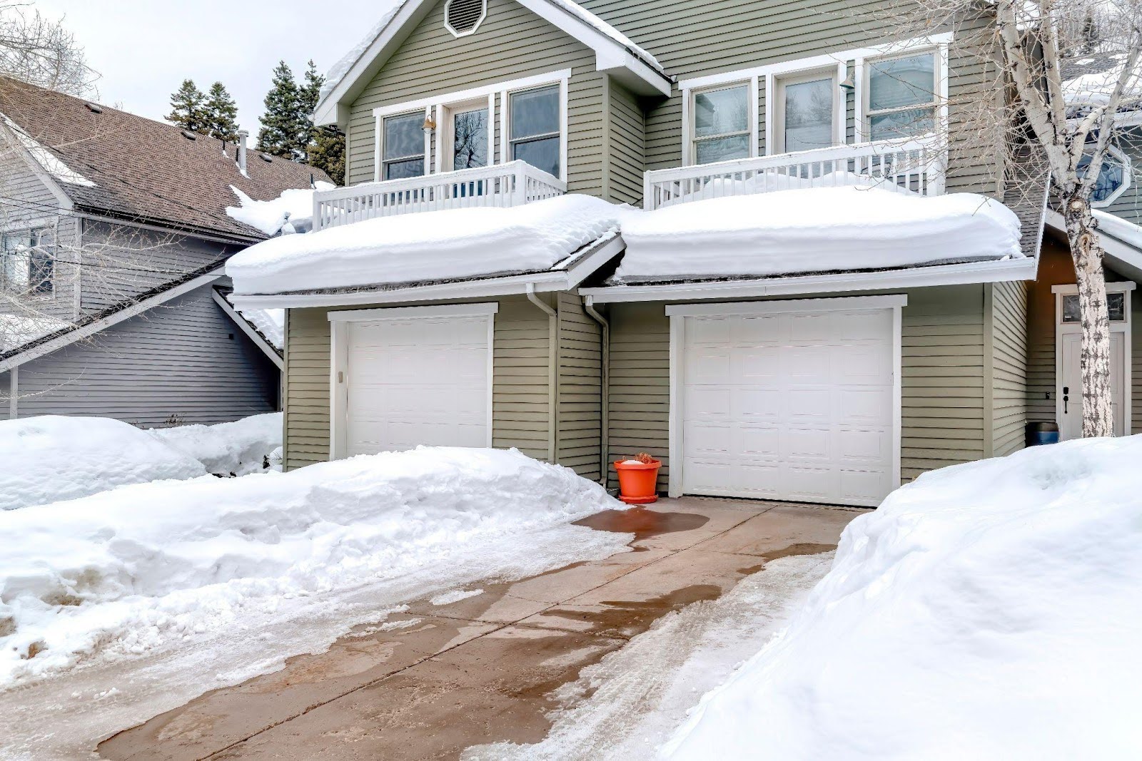 A snow-covered house with a garage set against a wintry backdrop
