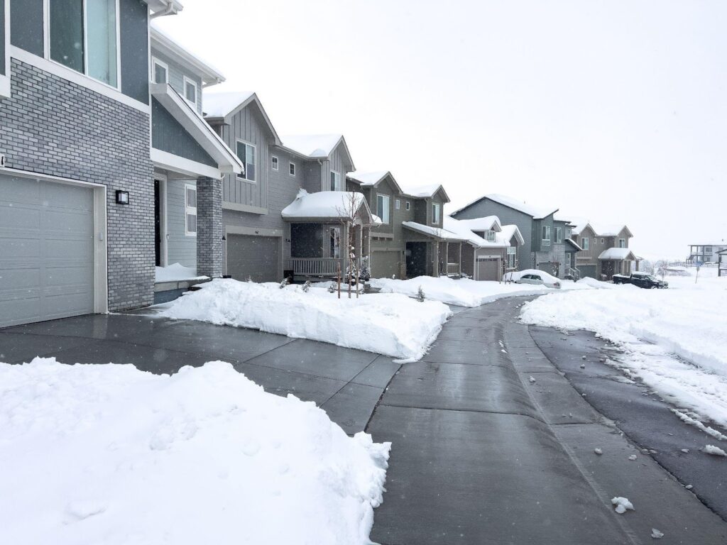 A snowy driveway stretches in front of a row of houses creating a serene winter scene