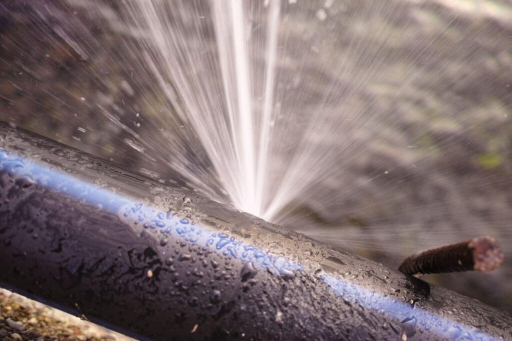 A water pipe sprays a stream of water into the air creating a misty effect around it