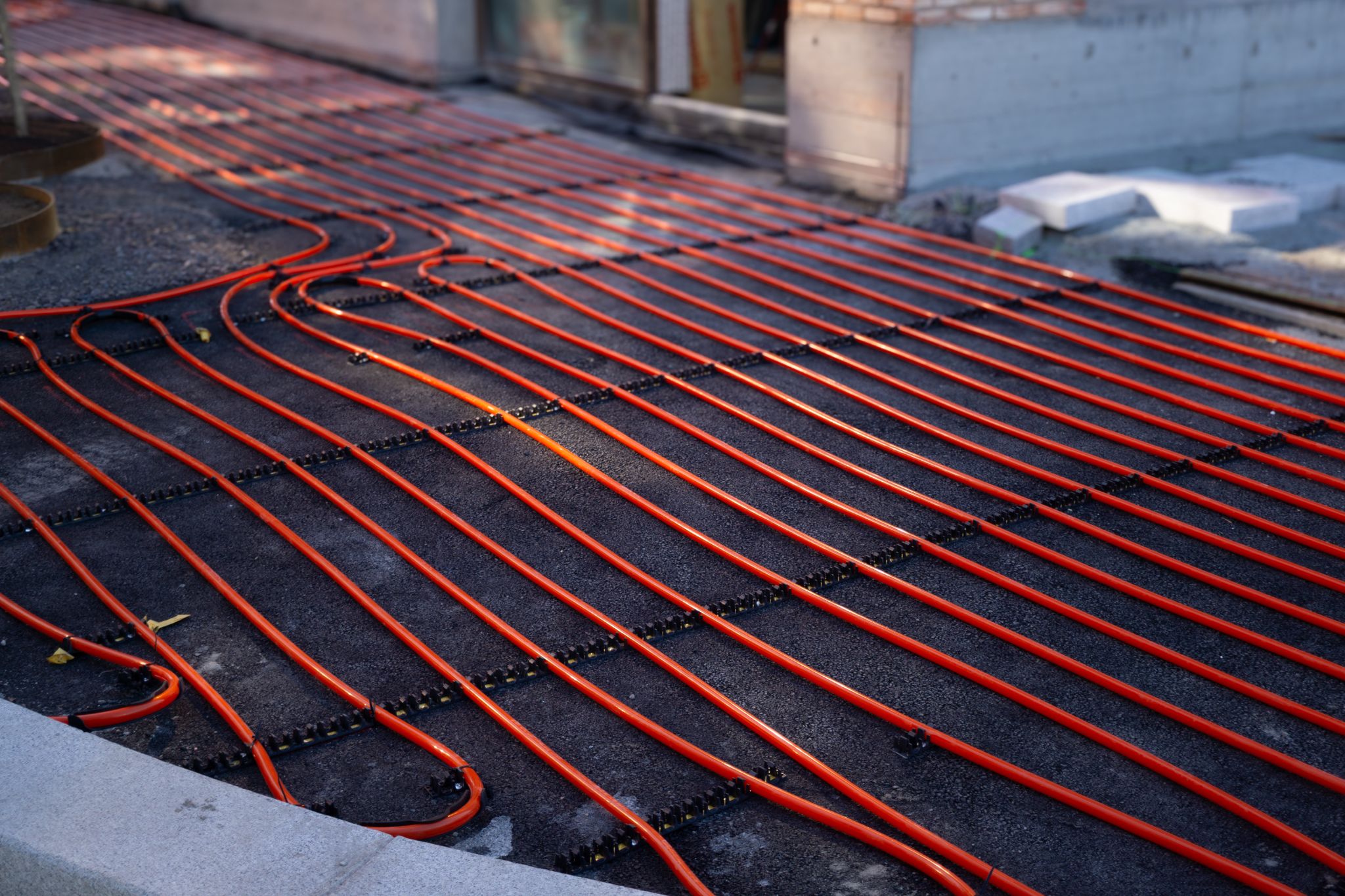 Installation of orange heating pipes for a snow melting driveway system.